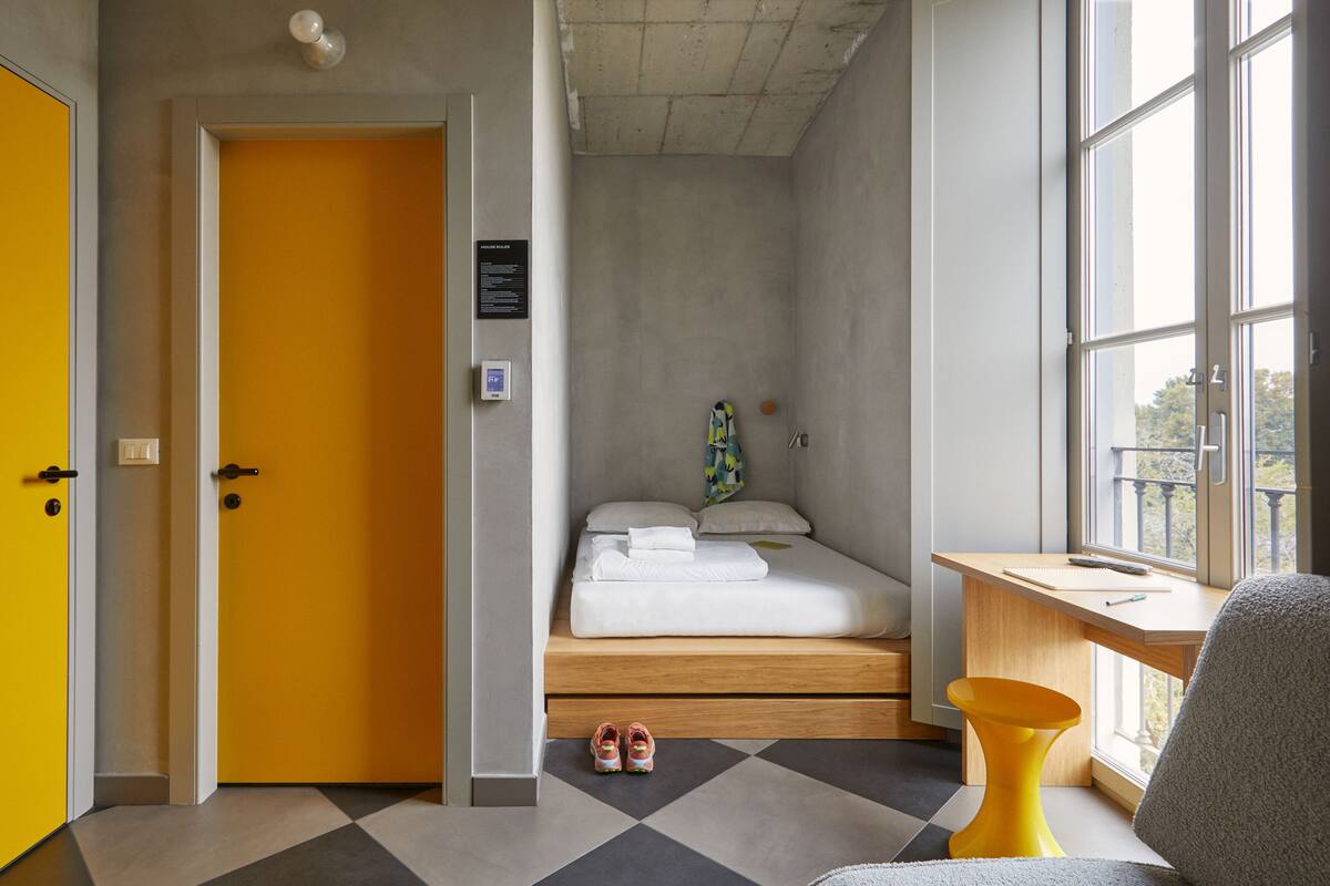 Una habitación con cama, escritorio, silla y ventana.