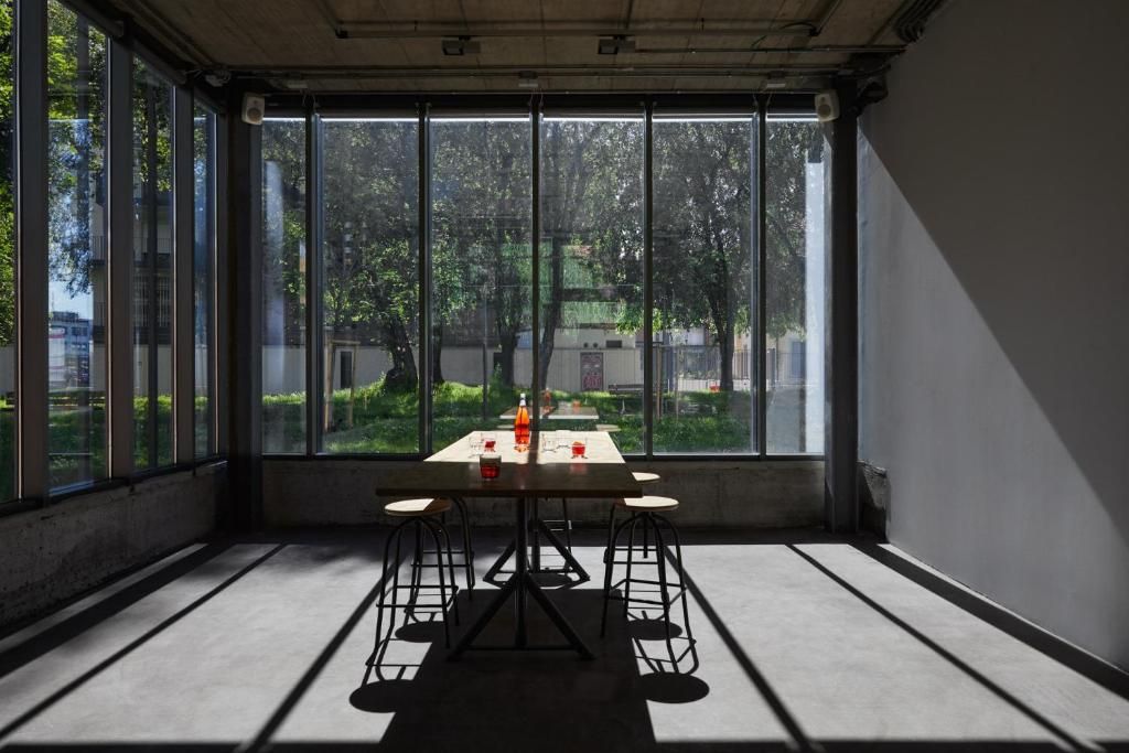Una habitación con una mesa y sillas, ventanas amplias y vista a zonas verdes.