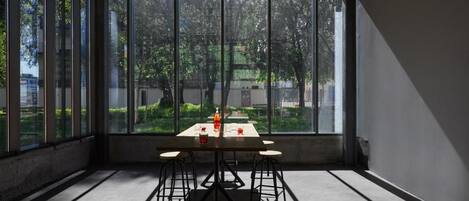 Una habitación con una mesa y sillas, ventanas amplias y vista a zonas verdes.