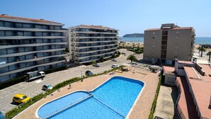 A hotel with a swimming pool, multiple floors, and a view of the beach and sea.
