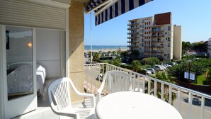 A balcony with a view of a beach and a parking lot.