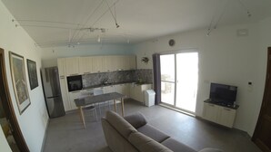 Een moderne woonruimte met keuken, eethoek en een groot raam.