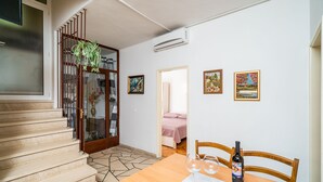 A dining area with a wooden table, two wine glasses, and a bottle of wine. There is a staircase with a glass door leading to another room. - Apartments Nikolina (LU) - Two-Bedroom Apartment with Terrace (Lumbarda)