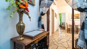 A room with a wooden desk, a brass vase with flowers, a patterned curtain, and a tiled floor. - Apartments Nikolina (LU) - Two-Bedroom Apartment with Terrace (Lumbarda)