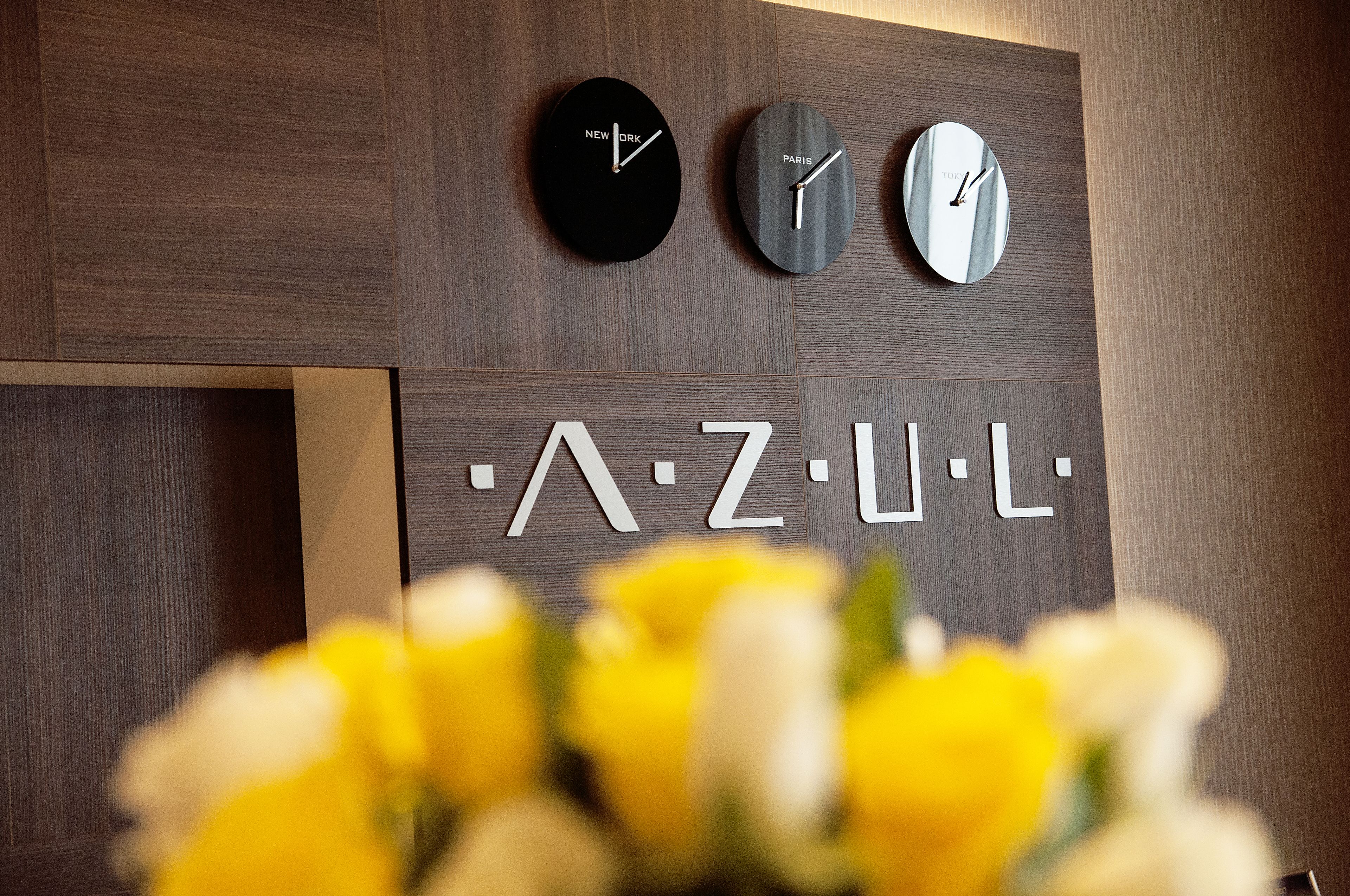 Three clocks with city names on them, mounted on a wall with a wooden panel design.