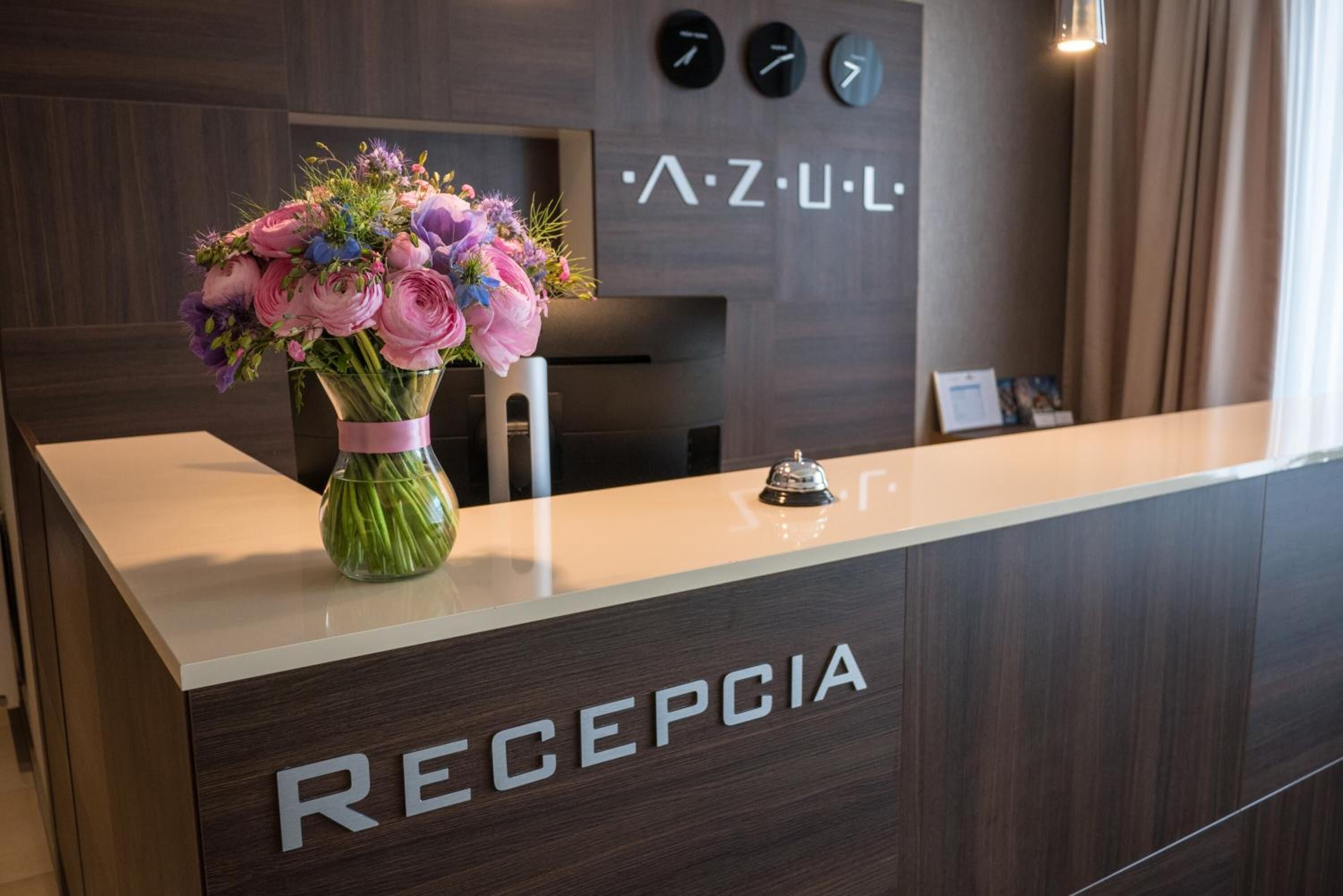 Een receptiebalie met een bloemenvaas en een klok aan de muur.