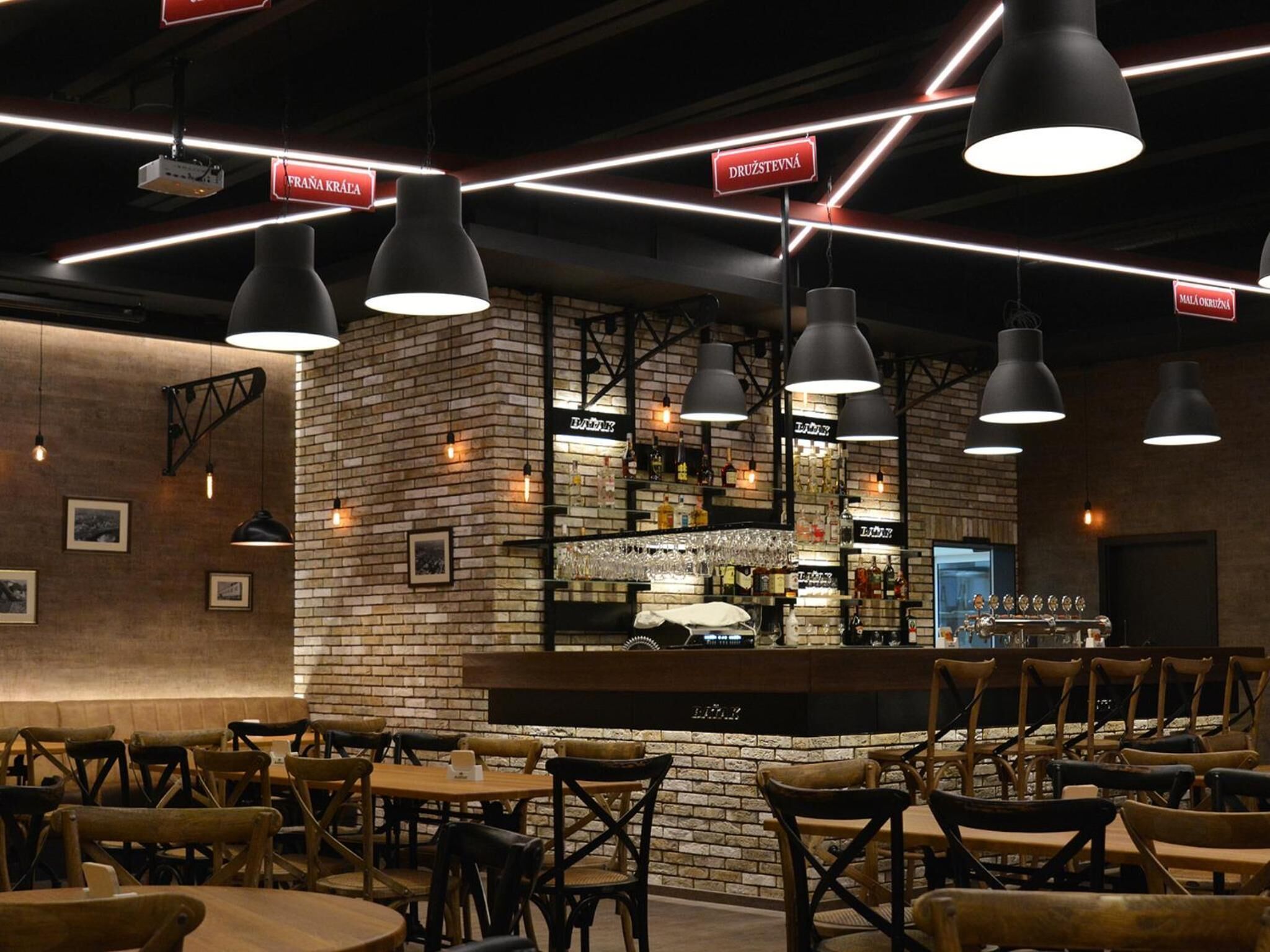 Un restaurante con paredes de ladrillo, lámparas colgantes y una zona de bar.
