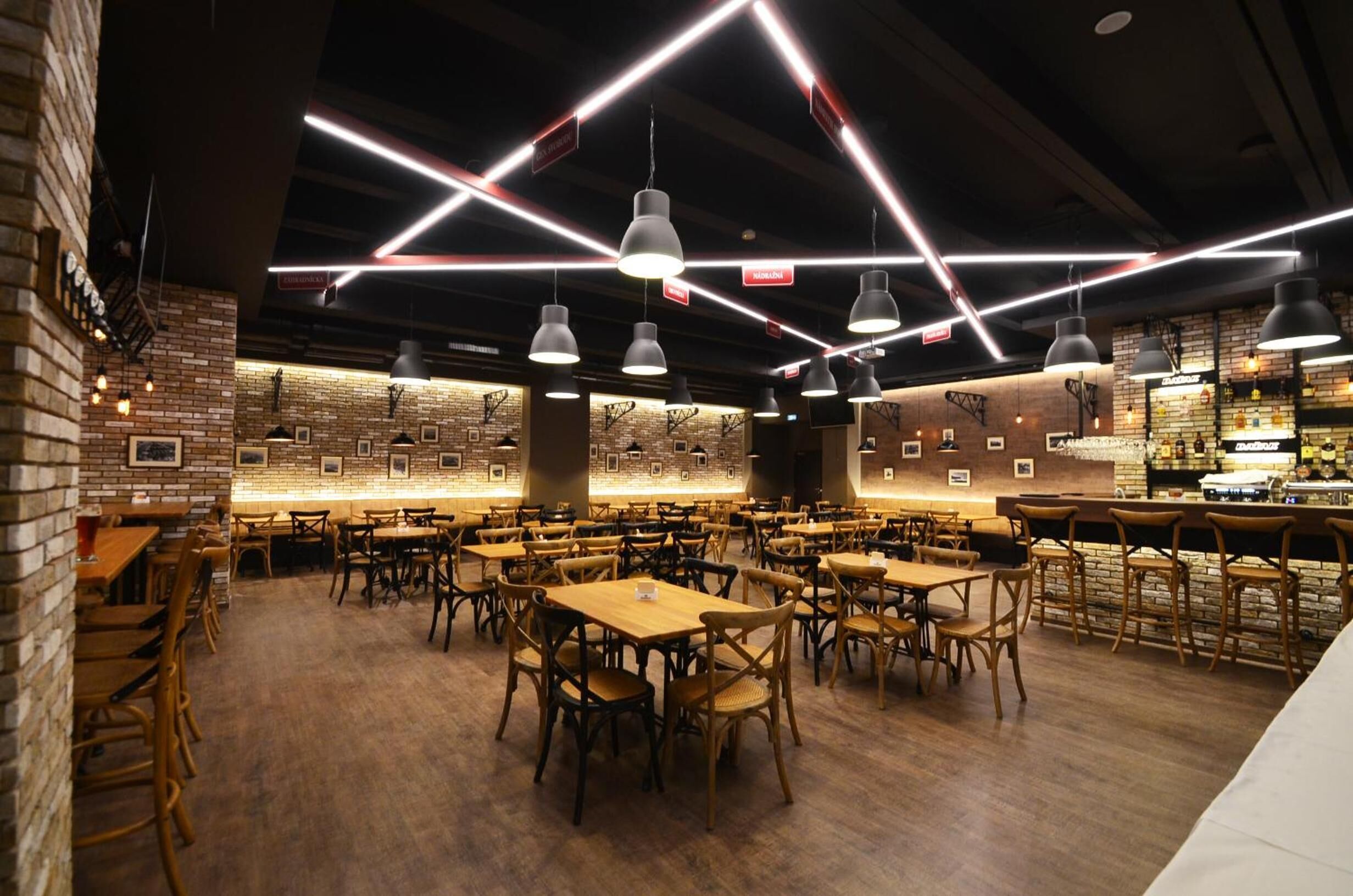 Un restaurante con paredes de ladrillo, mesas de madera y lámparas colgantes.