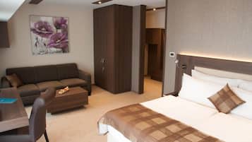 Ein modernes Hotelzimmer mit einem großen Bett, einer Couch, einem Esstisch und einem Blumenbild an der Wand.