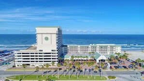 Un hôtel doté d’une tour centrale et d’un parking bordé de palmiers.