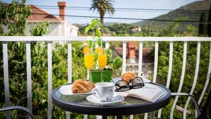 A balcony with a table set for breakfast, including croissants, a cup, and a book. - Villa Roza - Studio Apartment with Balcony (Mokosica)