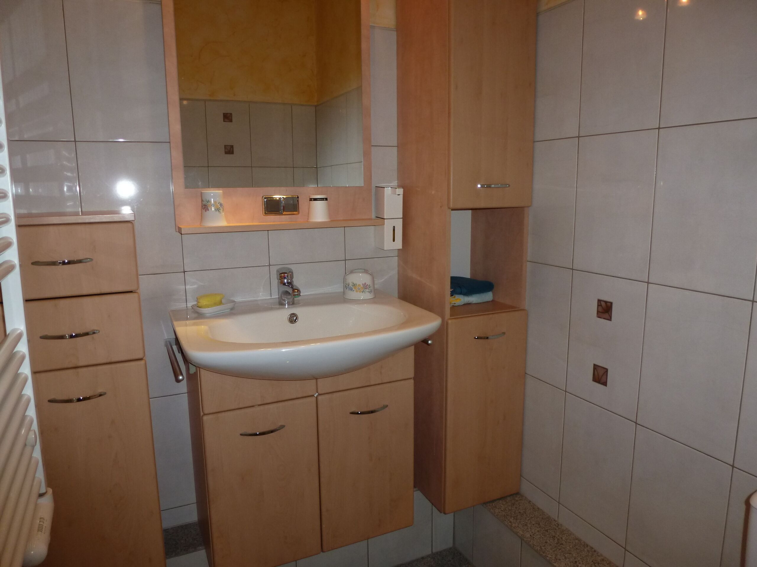 A bathroom with a sink, mirror, and wooden cabinets.