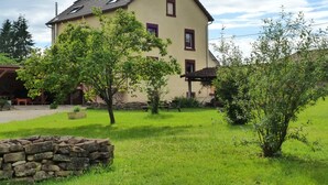 Ein zweistöckiges Haus mit einer Steinwand im Vordergrund, einem Rasen und einem klaren Himmel.