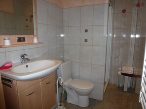 Une salle de bain comprenant un lavabo, des toilettes et un espace douche.