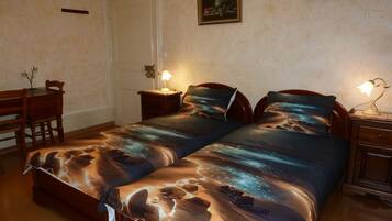 A bedroom with two beds, a desk, and a chair.
