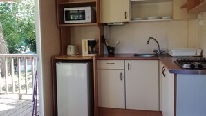 A compact kitchen with a microwave, coffee maker, and a small refrigerator. - Camping de Fléchat (Orcival)