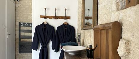 A rustic bathroom with wooden furniture, a stone wall, and a mirror.