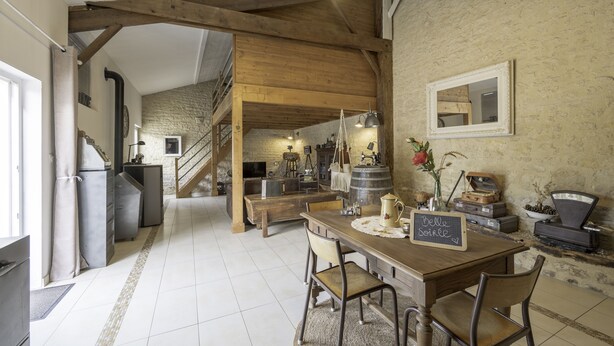 A rustic kitchen with a wooden table, chairs, and a chalkboard sign. - L'Echappee Vendeenne Chambres d'Hotes (Saint-Aubin-la-Plaine)
