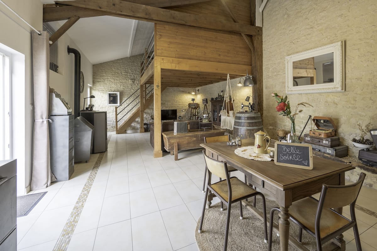 Une cuisine rustique avec une table en bois, des chaises et un panneau d’affichage noir.