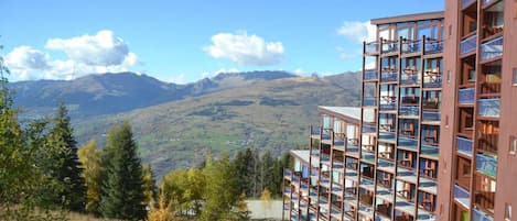 Un edificio de varios pisos con balcones, con montañas al fondo.