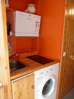 A compact laundry area with a washing machine, a drying rack, and a small sink.
