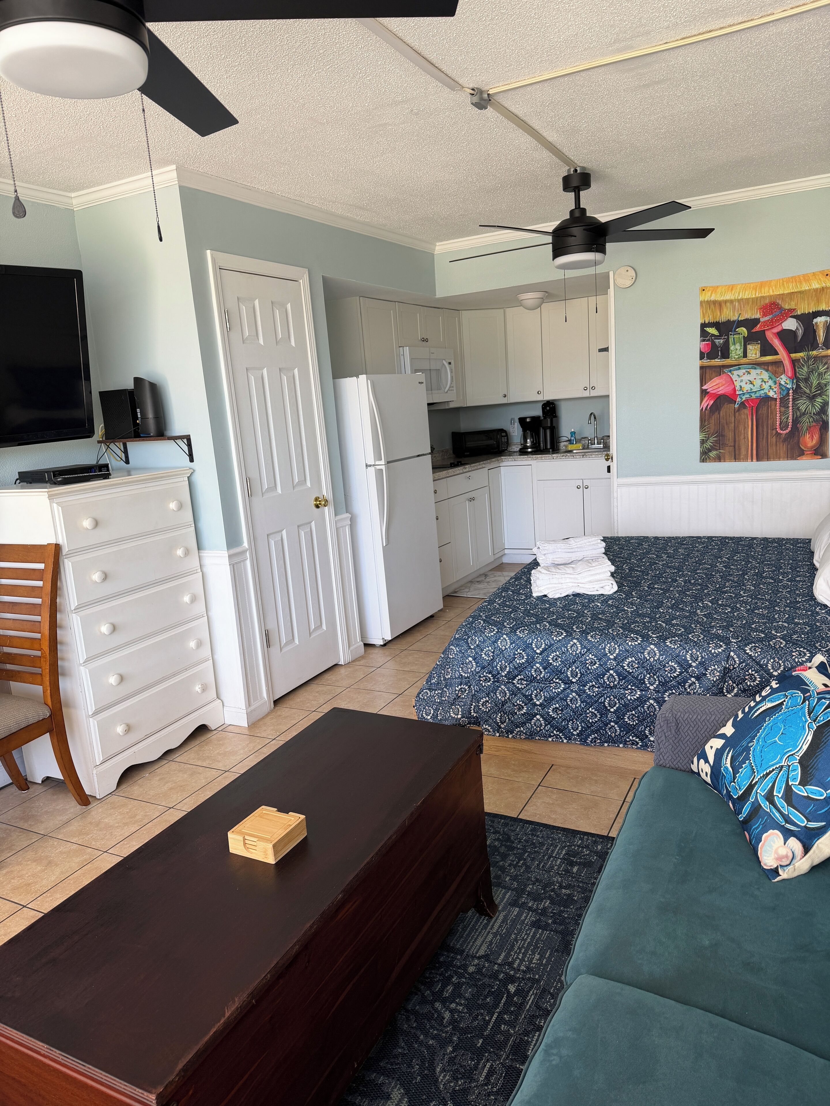 A compact living space with a kitchenette, a sofa, a coffee table, and a ceiling fan.
