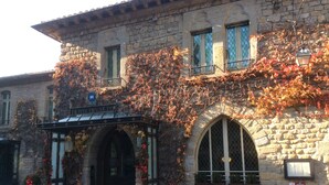 A historic stone building with a covered entrance, arched windows, and ivy-covered walls. - Carcassonne, elegant apartment overlooking central square (Carcassonne)