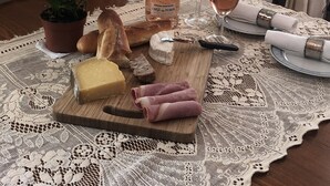 A table set with a bottle of wine, glasses, cheese, bread, and a potted plant. - Carcassonne, elegant apartment overlooking central square (Carcassonne)