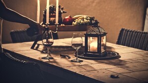 Una mesa con copas de vino, una vela y un farol.