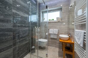 Une salle de bain moderne avec une douche à parois de verre, des toilettes blanches, un meuble-lavabo et un porte-serviettes.