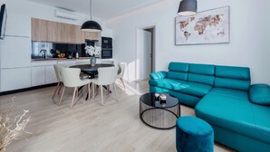 Un espacio habitable moderno con cocina, comedor y un sofá color turquesa.