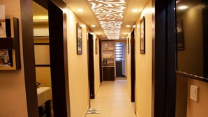 A hotel hallway with framed pictures on the walls, a tiled floor, and a ceiling with a decorative light fixture. - Hotel Rudra View & Spa (Kathmandu)