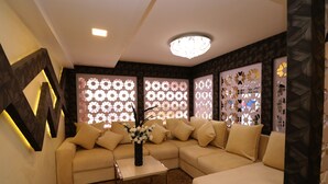 A modern living room with a sectional sofa, decorative panels, and a vase of flowers. - Hotel Rudra View & Spa (Kathmandu)