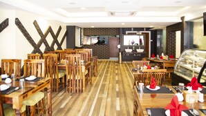 A restaurant with wooden furniture, a central counter, and a dessert display. - Hotel Rudra View & Spa (Kathmandu)