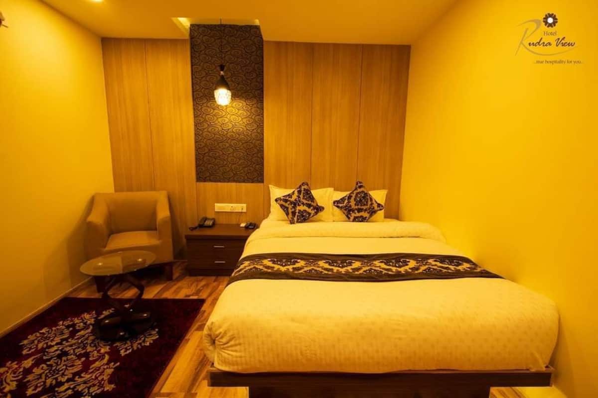 A hotel room with a bed, a chair, a nightstand, and a patterned wall.