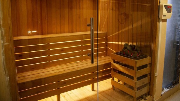 A wooden sauna with a bench and a small wooden shelf with items on it. - Hotel Rudra View & Spa (Kathmandu)