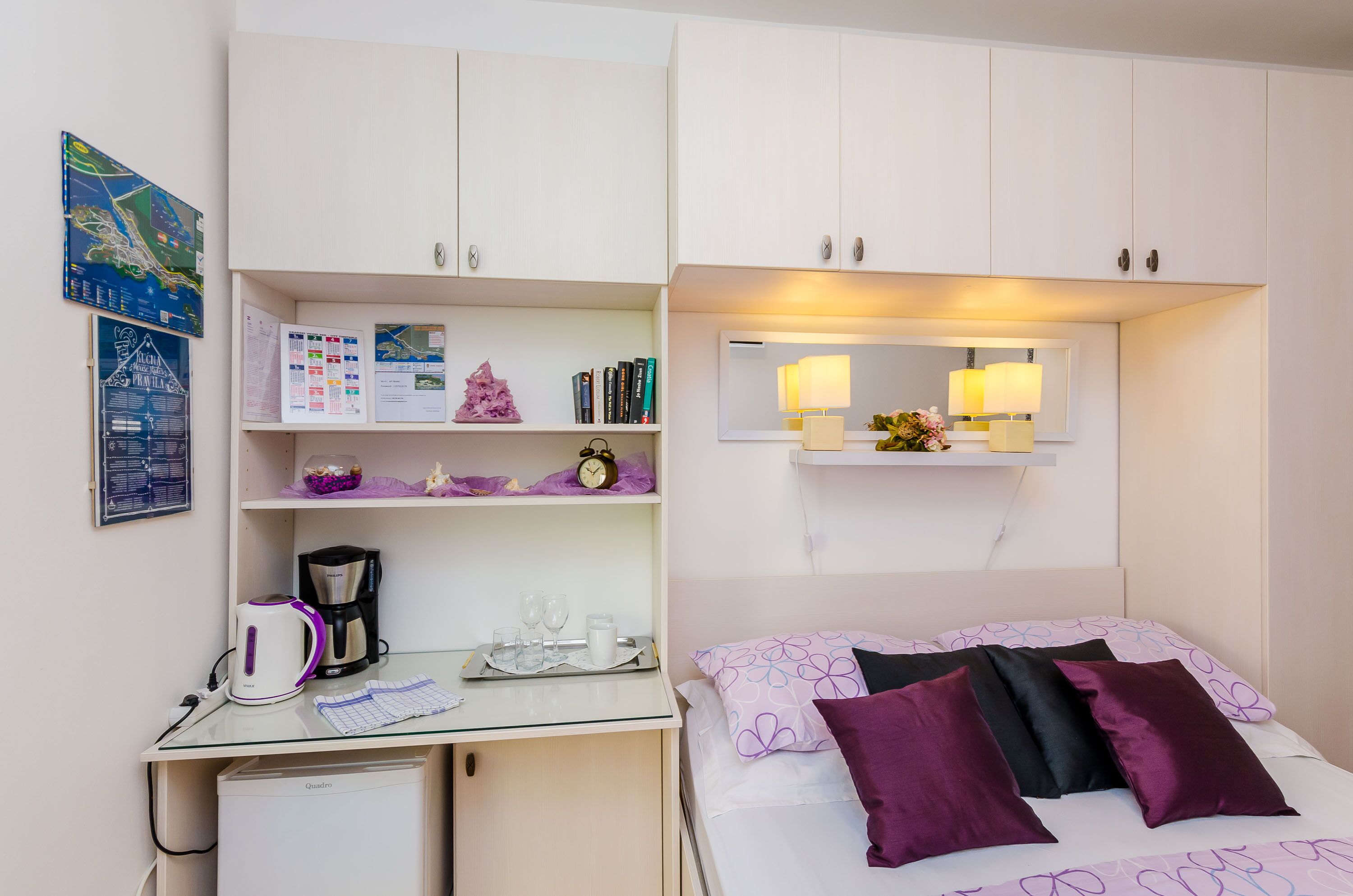 A neatly organized room with a bed, a desk, and a small refrigerator.