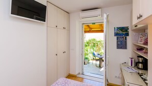 A compact room with a bed, a desk, a chair, and a TV mounted on the wall. - Apartments and Room Frane - Double Room (Dubrovnik)