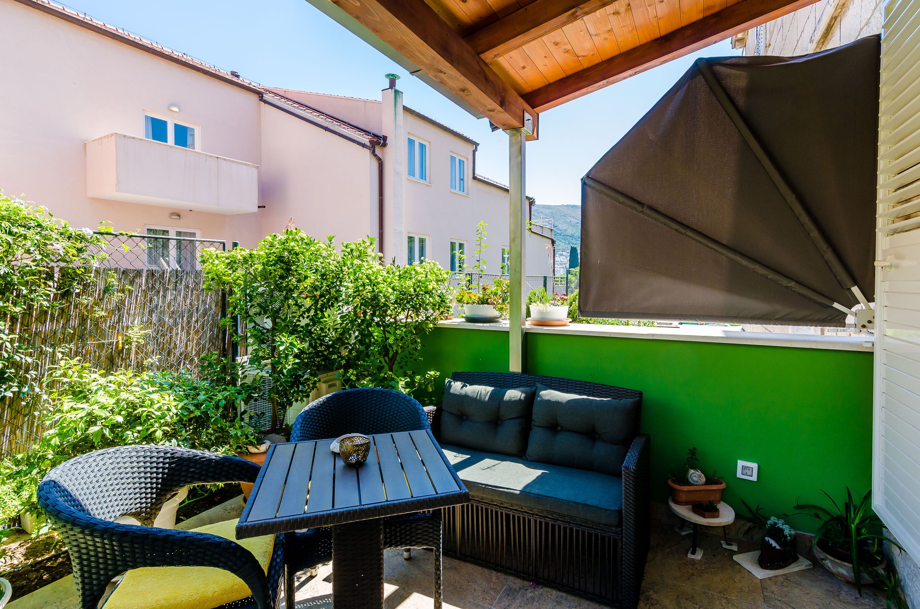 A patio with a table and chairs, a sofa, and potted plants.