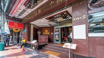 A hotel entrance with a sign for Scala Hostel, a reception desk, and a staircase leading inside.