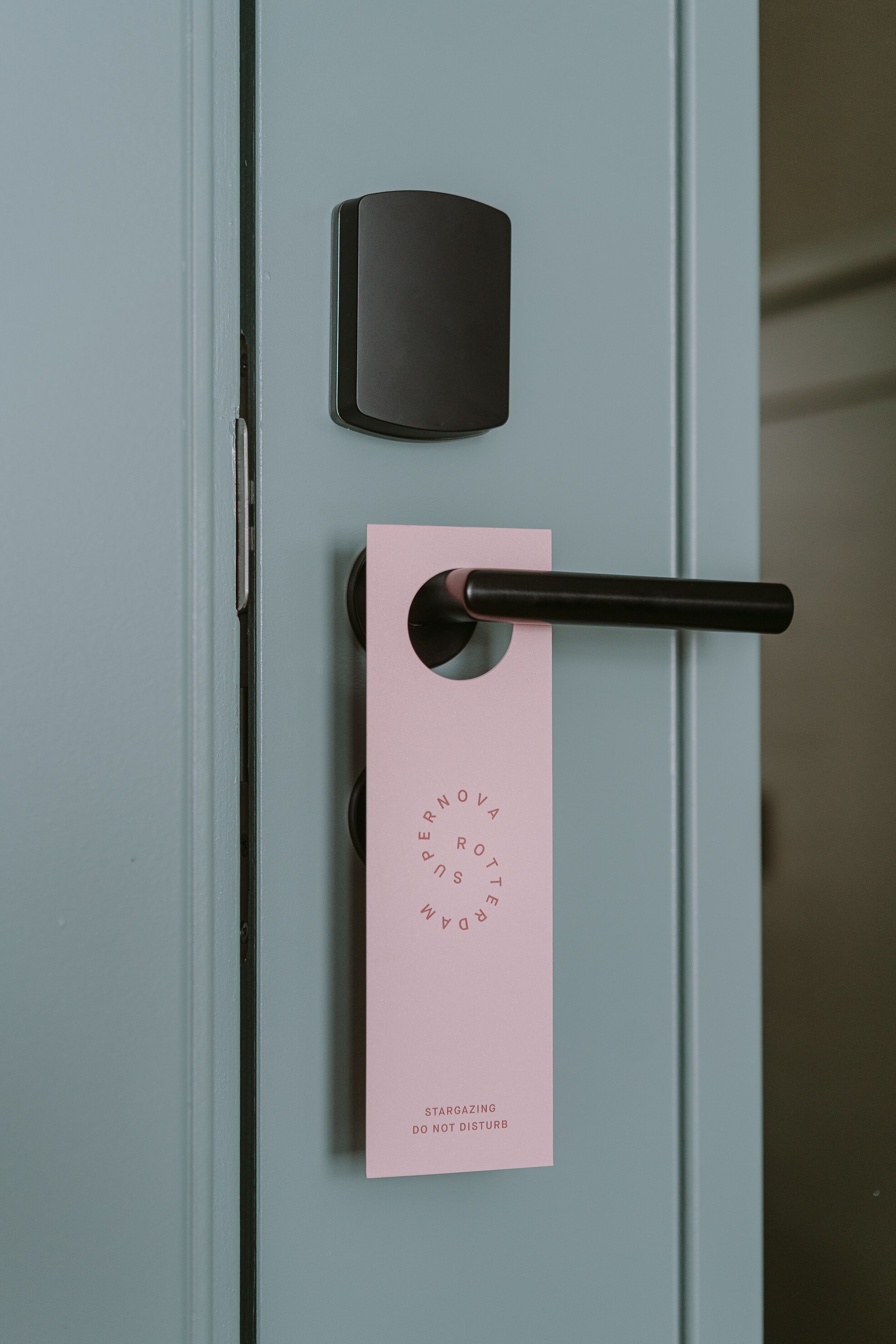 A door with a black handle and a pink card with text.