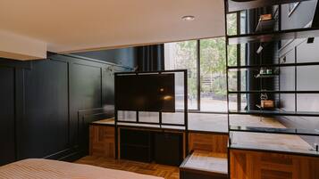 A modern bedroom with a large bed, built-in TV, and a view of the outdoors.