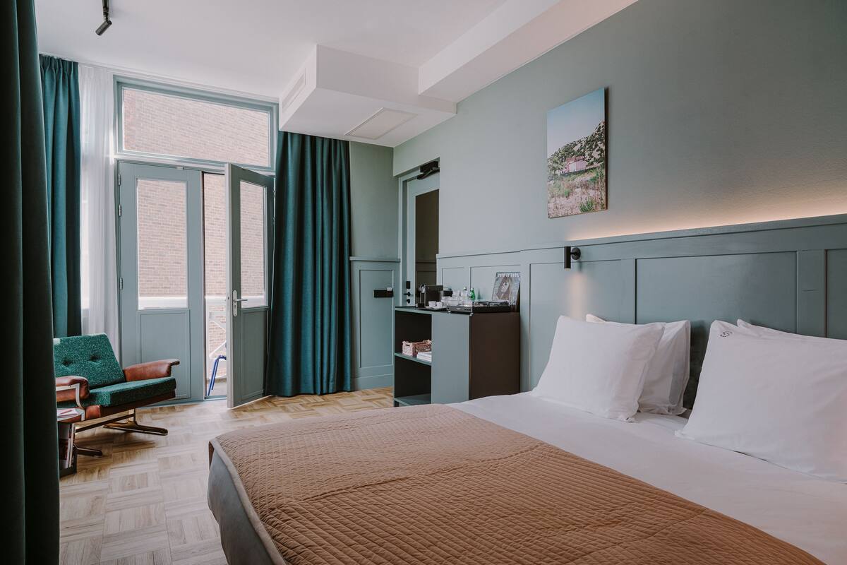 Ein Hotelzimmer mit Bett, Schreibtisch, Stuhl und einem Vorhangfenster.