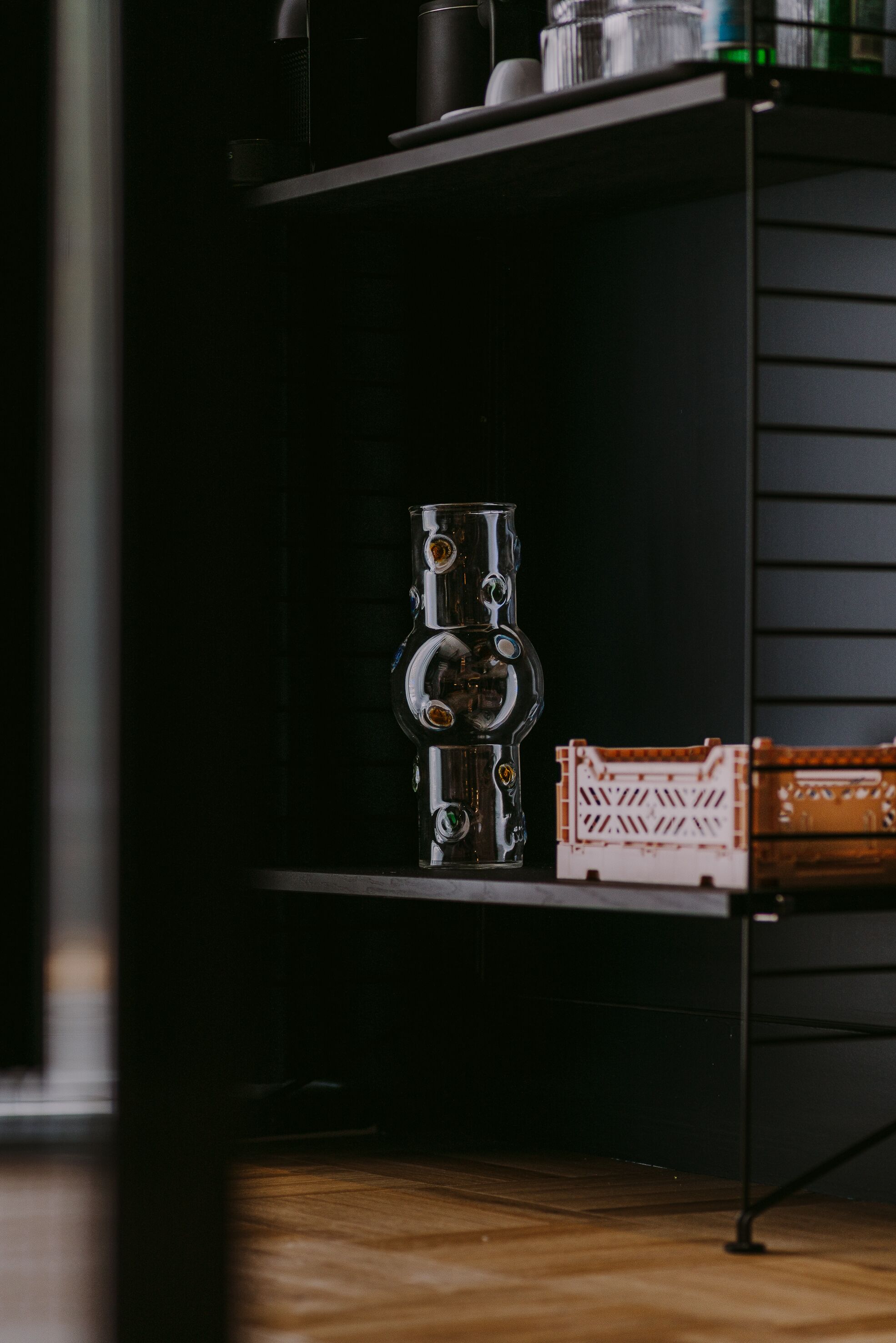 A shelf with a metallic object and a crate.