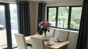 Un comedor con una mesa de madera dispuesta para cuatro personas, rodeada de sillas, y un ventanal que ofrece vistas al exterior.