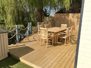 A wooden deck with a table and chairs, surrounded by a wooden fence and a rope barrier. - The Lily Pad Riverside Apartment (Bidford-on-Avon)