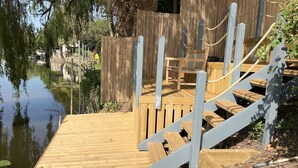 Un muelle de madera se extiende sobre aguas tranquilas, con una escalera de madera que sube a una plataforma.