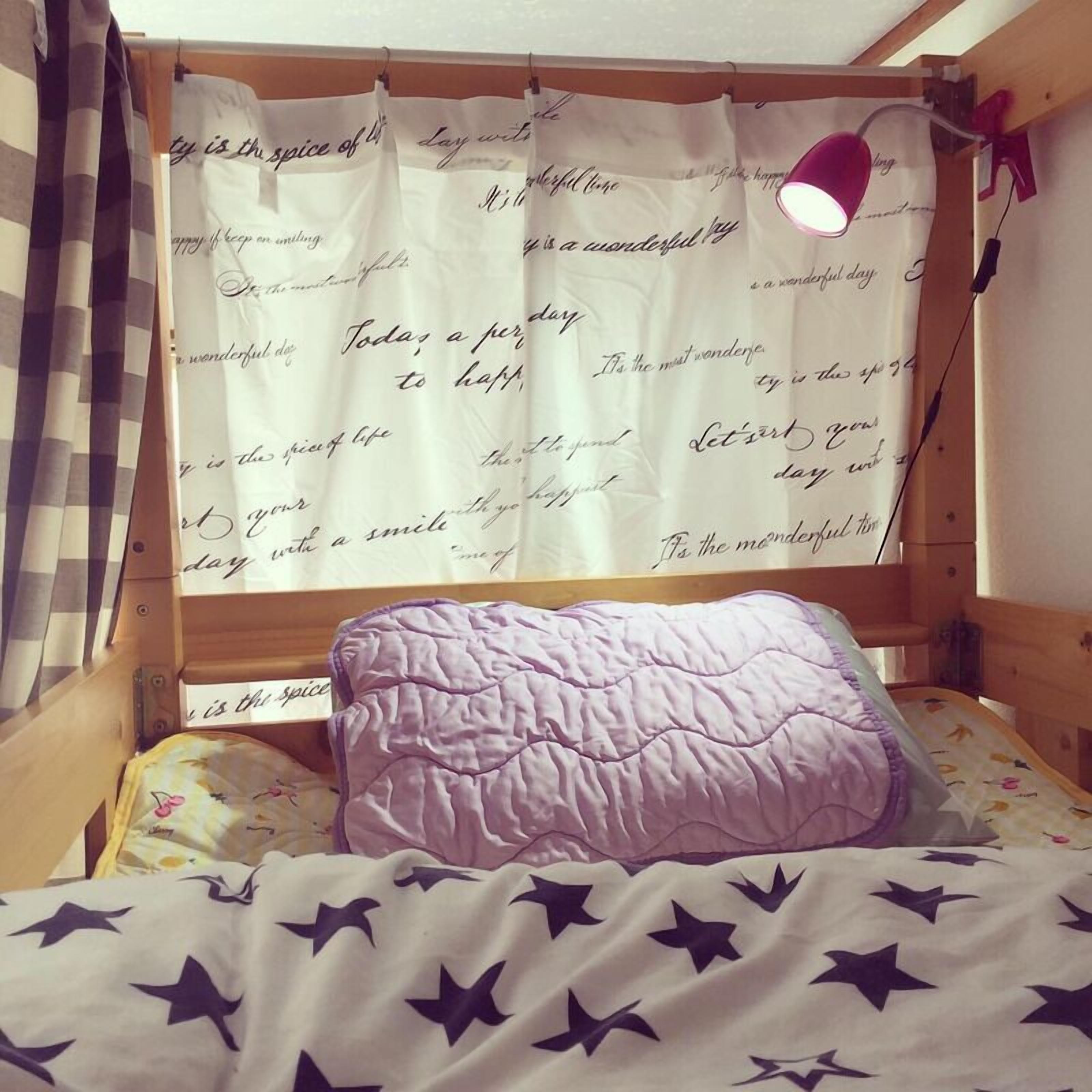 A bedroom with a bed, a window with curtains, a bedside lamp, and a wall with motivational quotes.
