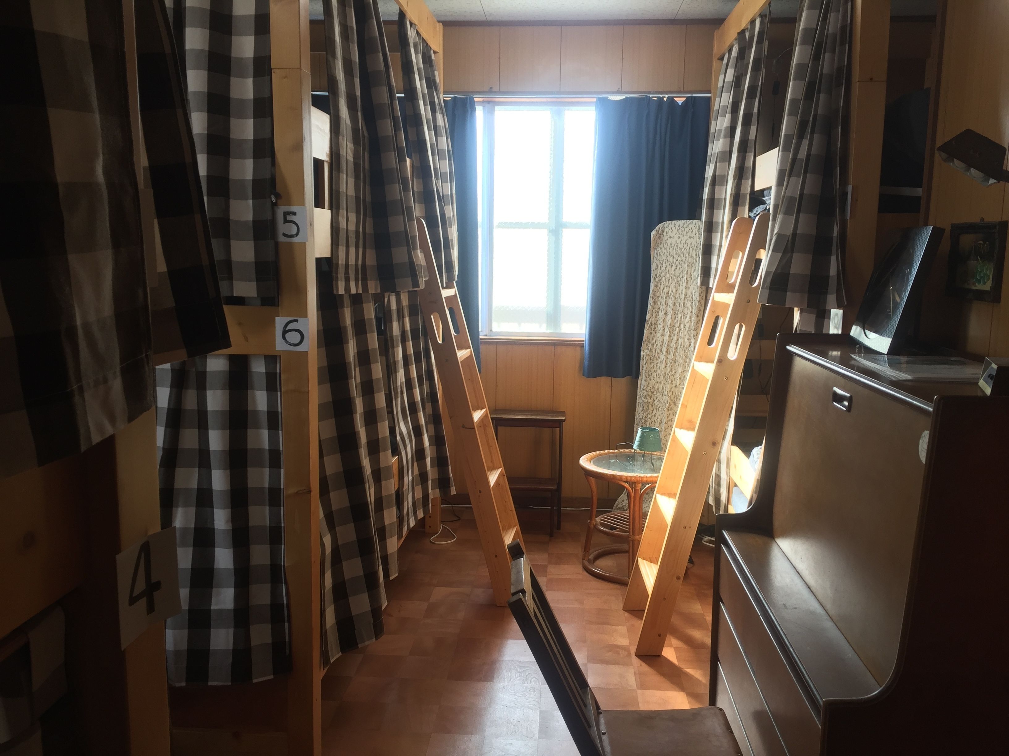 A room with bunk beds numbered 4, 5, and 6, a chair, and a desk with a computer.