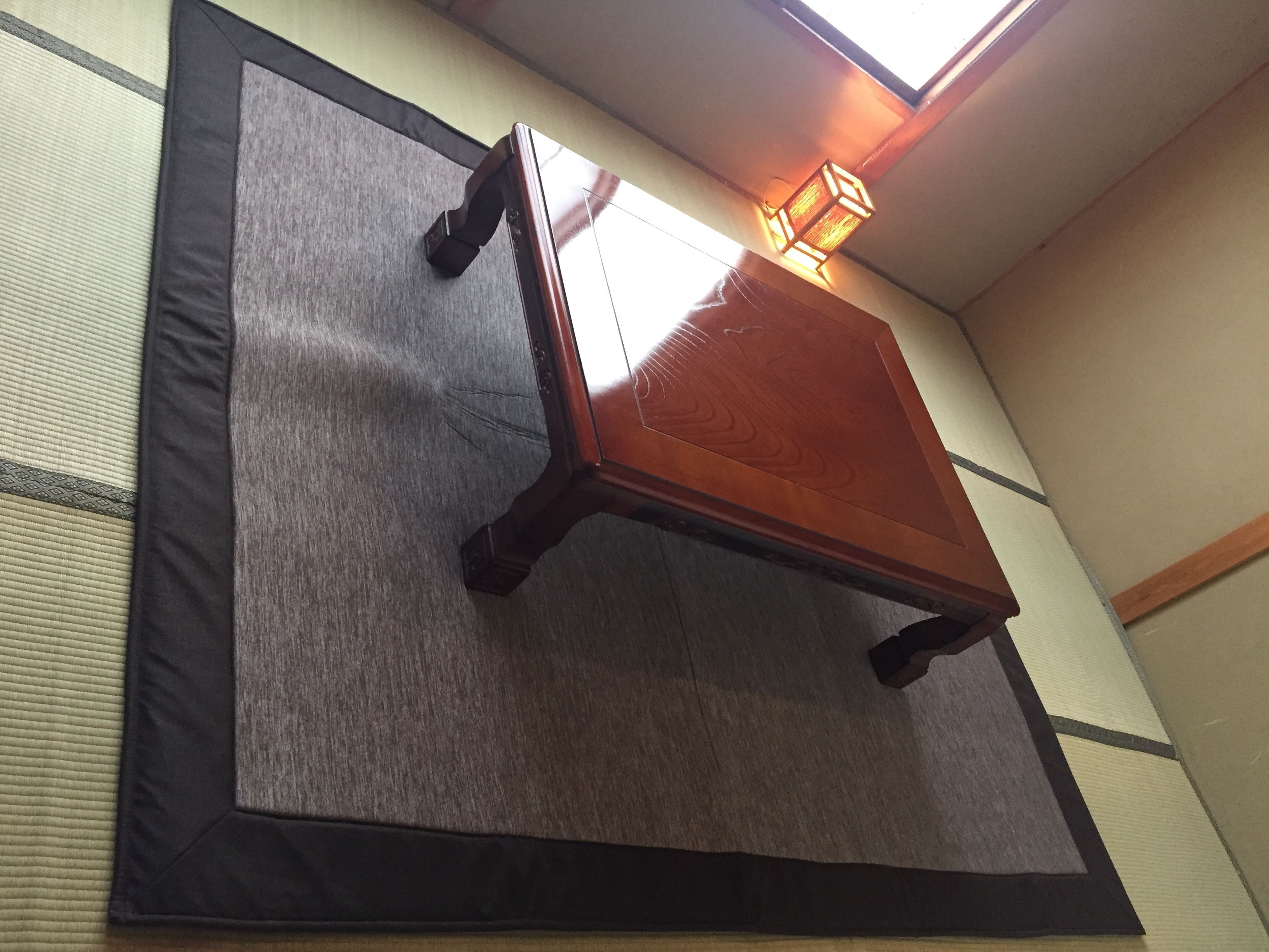 Una habitació amb tatami, taula de fusta i un llumí penjant.